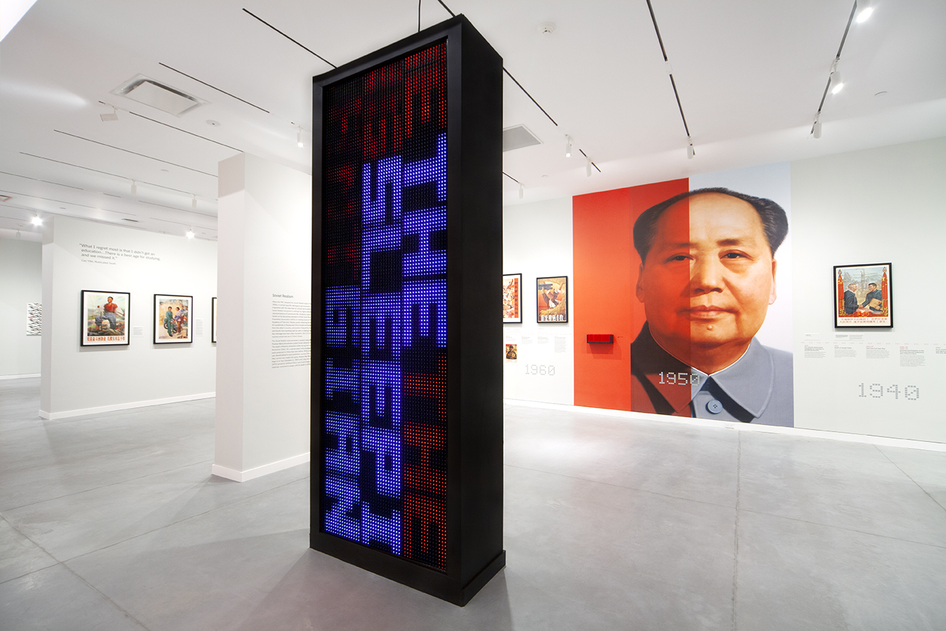 An imposing photo of Mao Zedong on a wall overlaid in red and a giant digitized screen of the exhibit facing him.