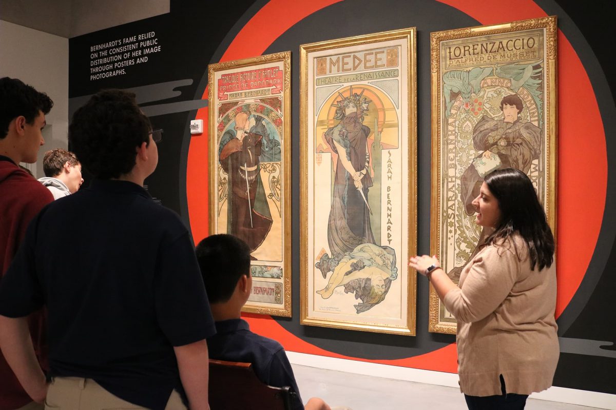 photograph of a group of students and an educator standing in front of three posters