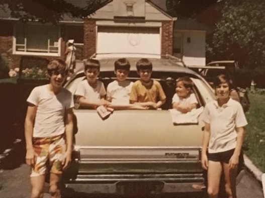 photograph of 6 children around the trunk of a car