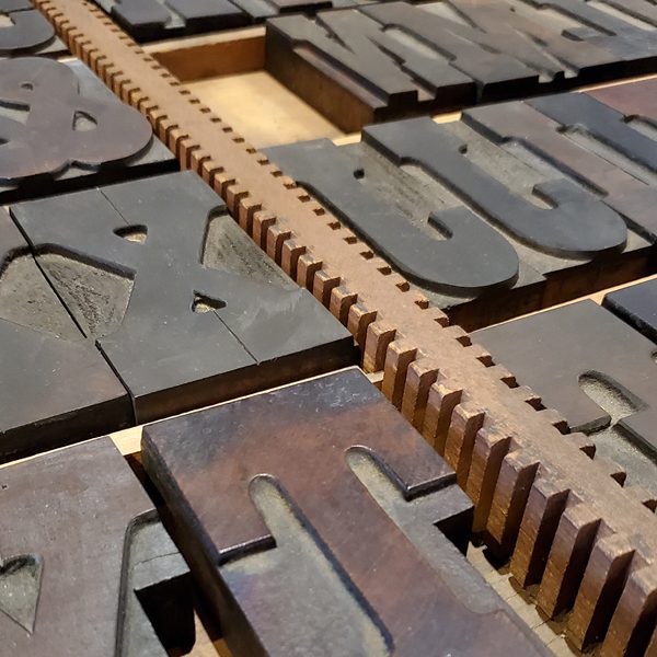 A close-up of wood-type lettering in a storage drawer.