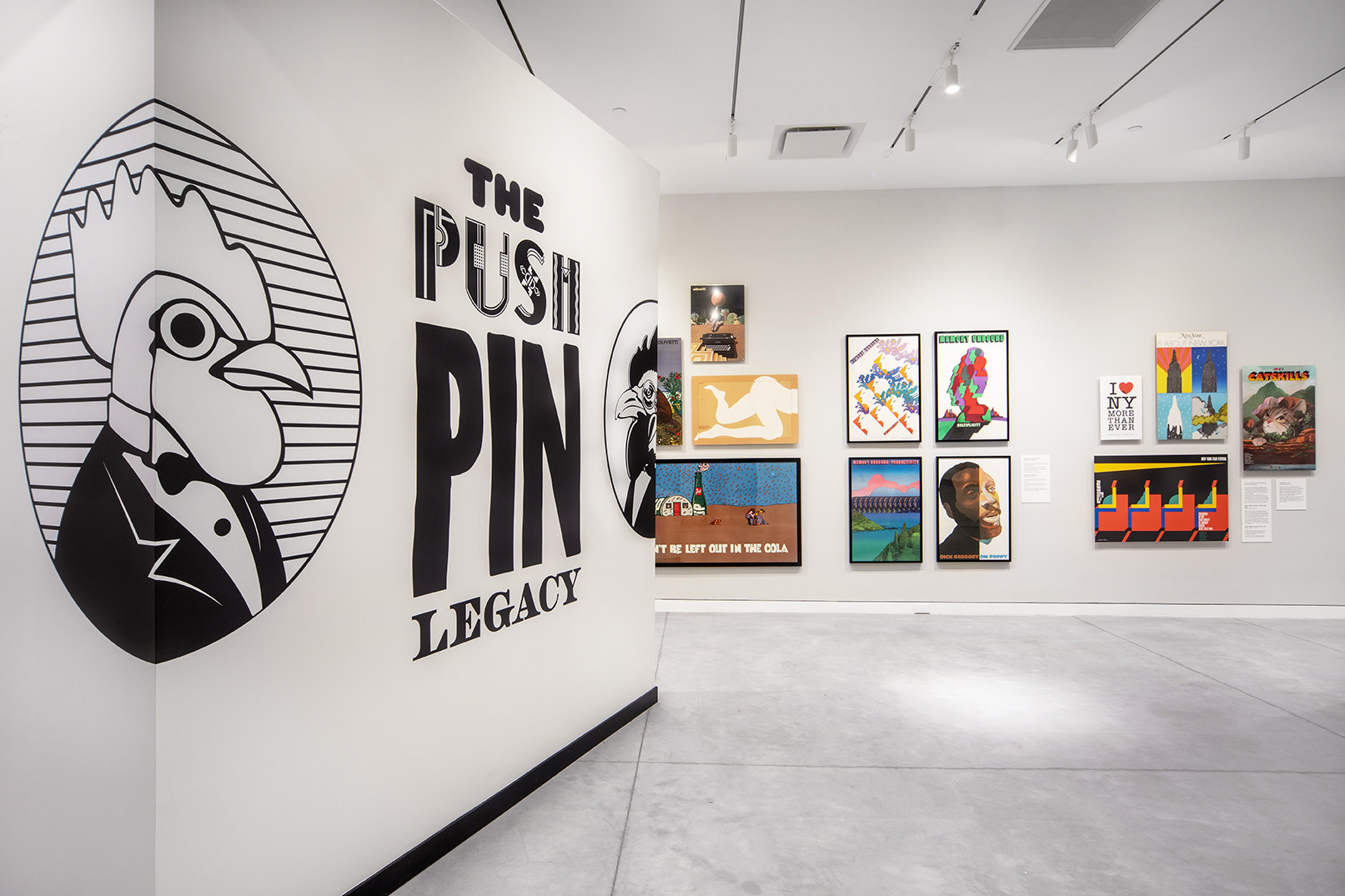 Peering into the Push Pin show by a chicken graphic dressed in a tux, directly ahead a white wall of colorful framed posters.
