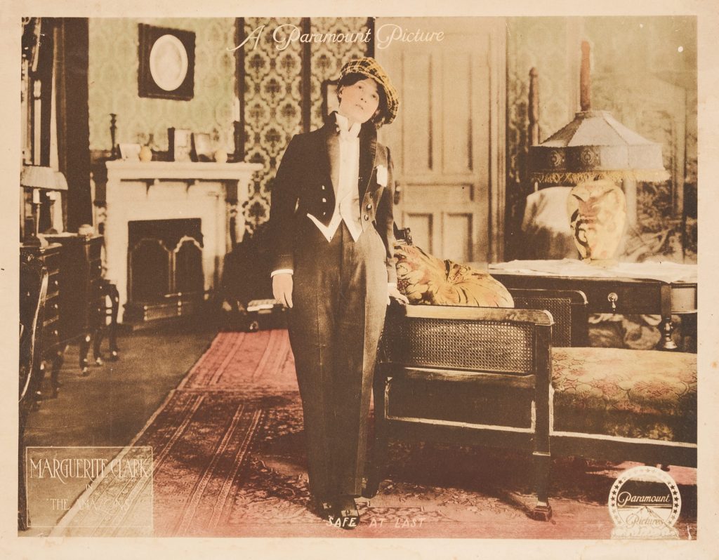 photographic image of a woman in a men's tuxedo in a lavish living room