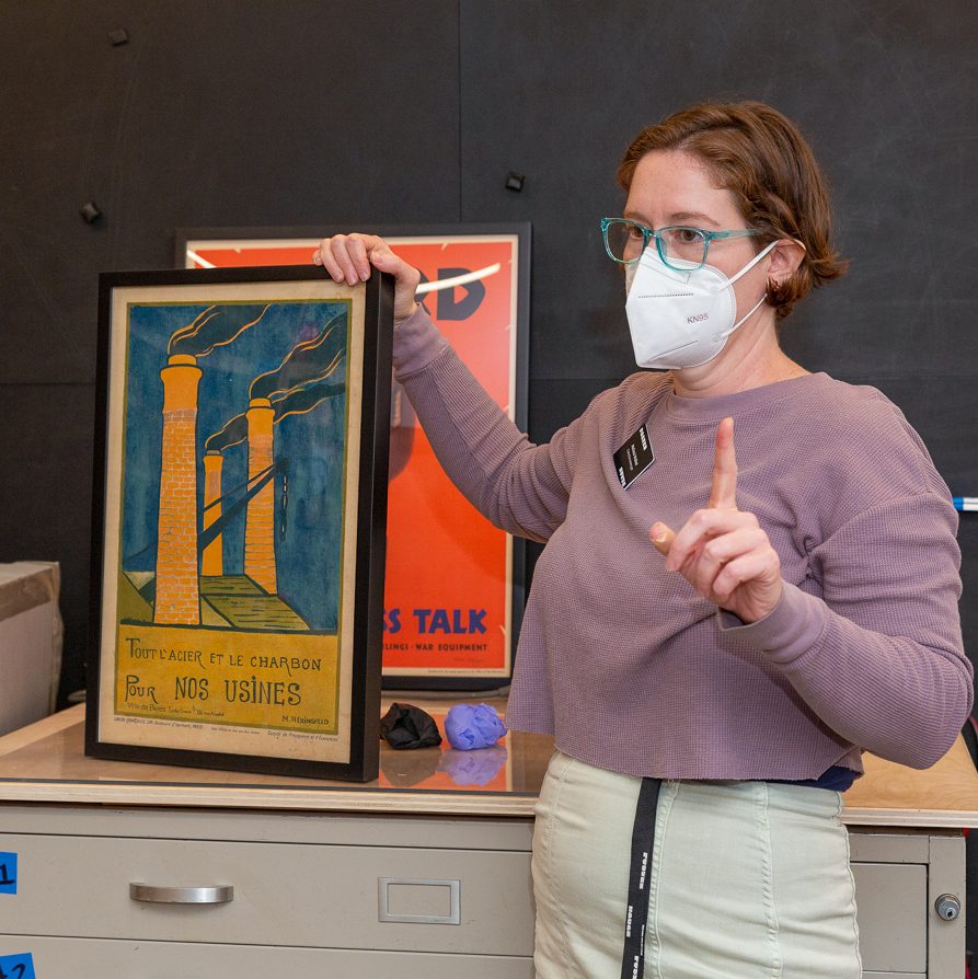 An image of a woman standing with a framed poster image.