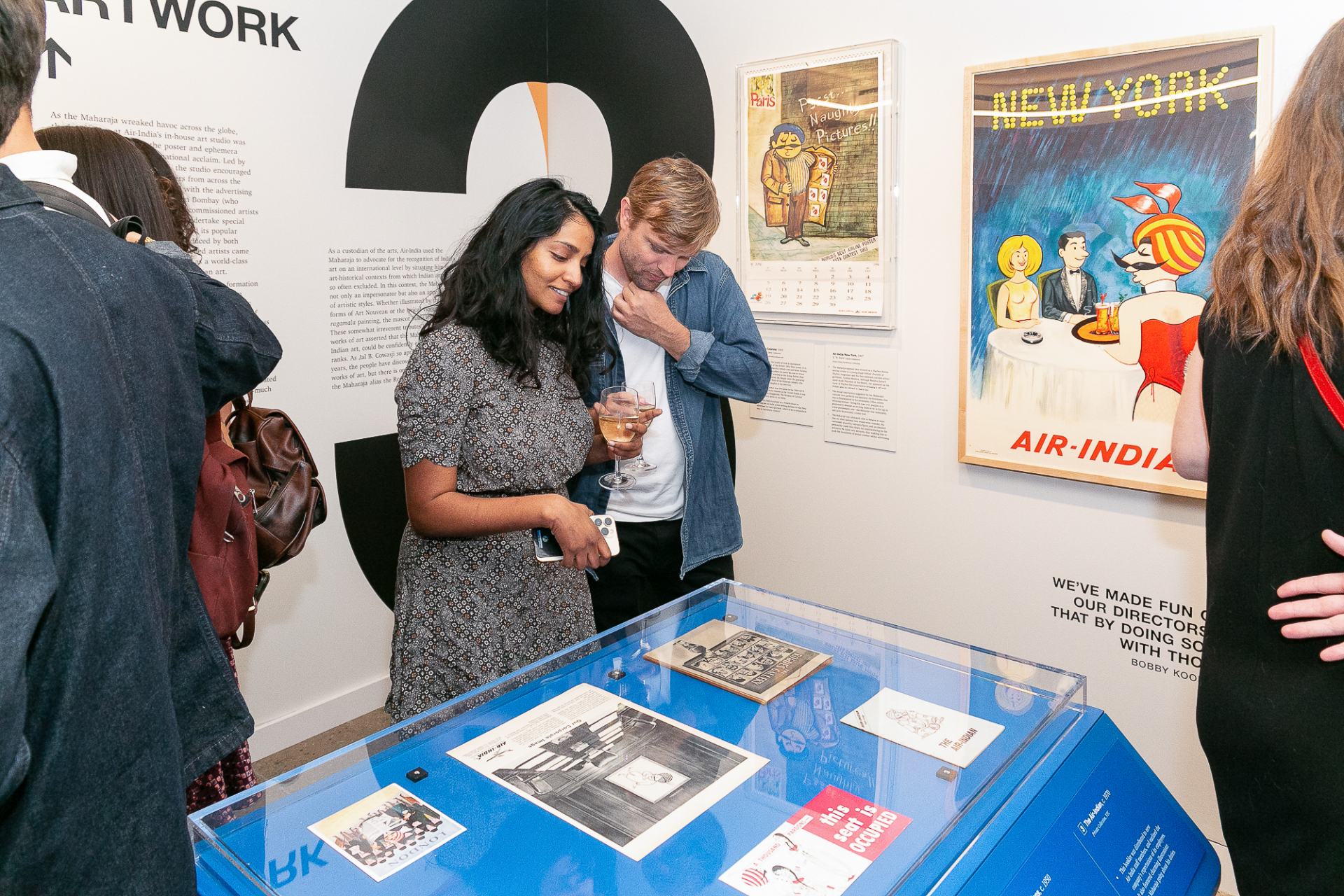 A couple looking at Air-India ephemera in a glass case at a museum gallery.