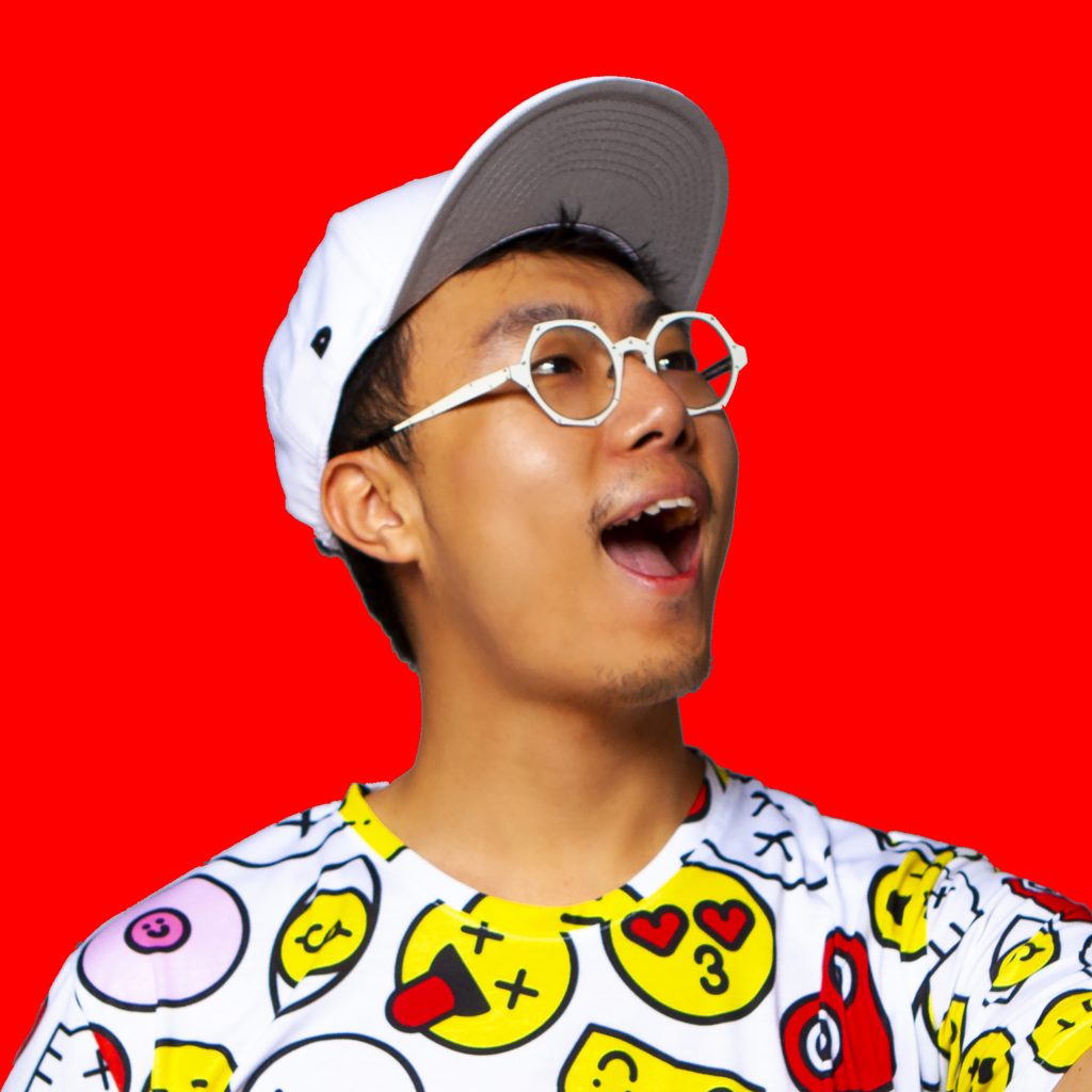 A headshot of an Asian person smiling with their head tilted upward wearing white glasses, a white baseball cap, and a white t-shirt with a variety of yellow, pink, and red shapes made into faces, on a red background.
