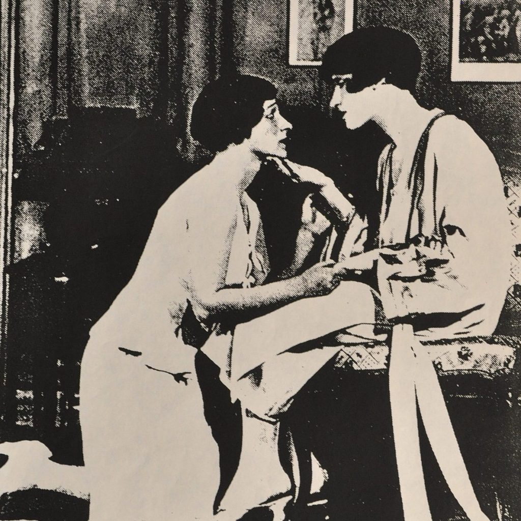Two women look at each other lovingly in a parlor