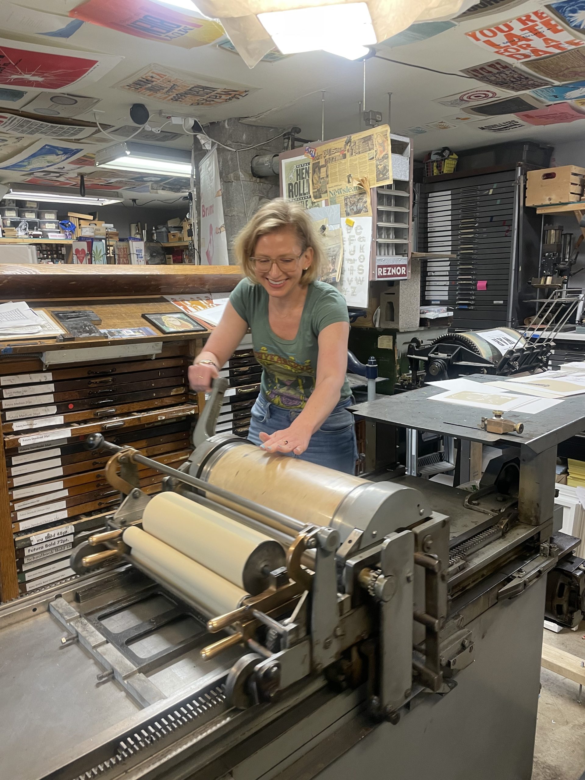 Photograph of a woman operating a letterpress printing press.