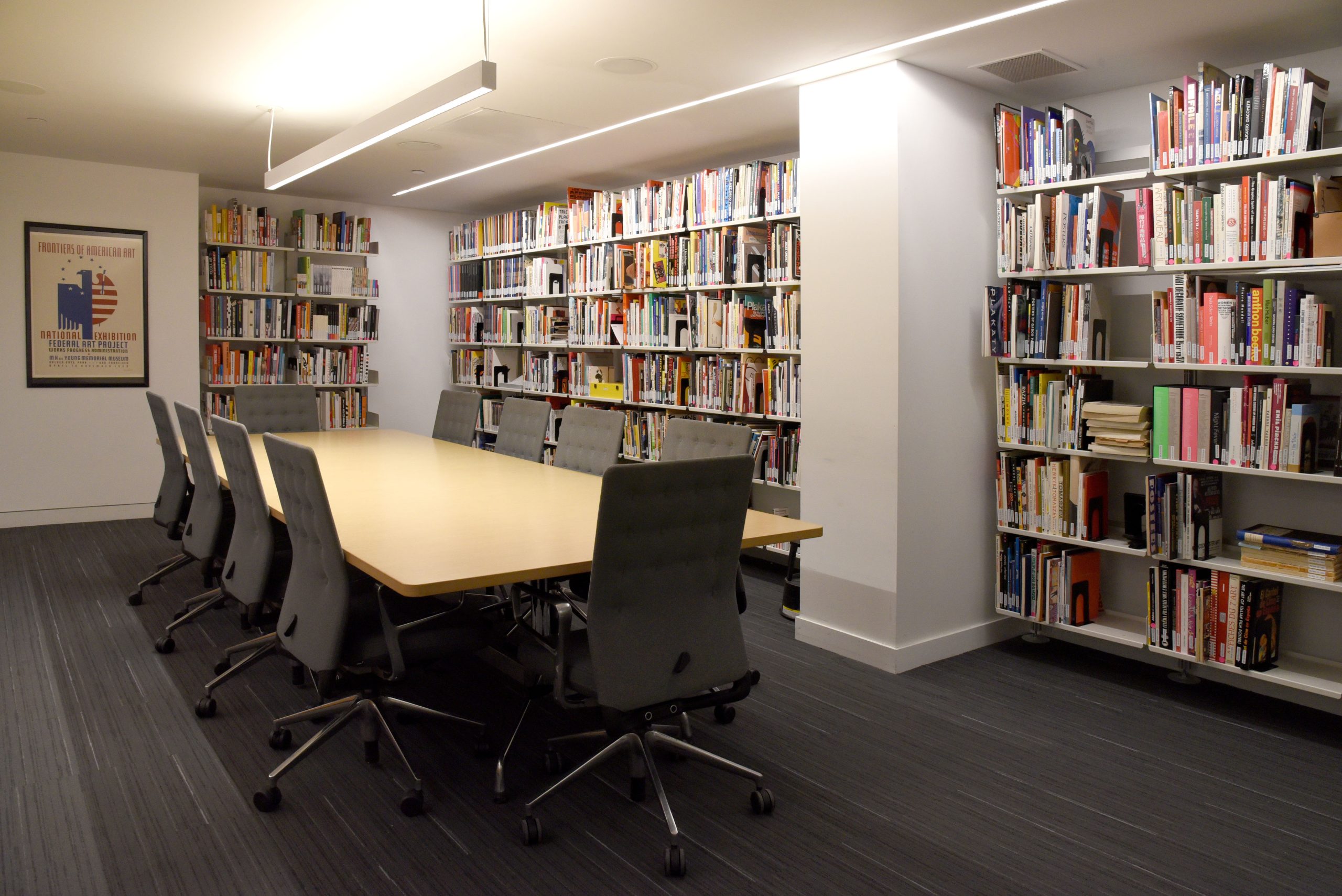 A photo of a library with books on shelves and a conference table with chairs