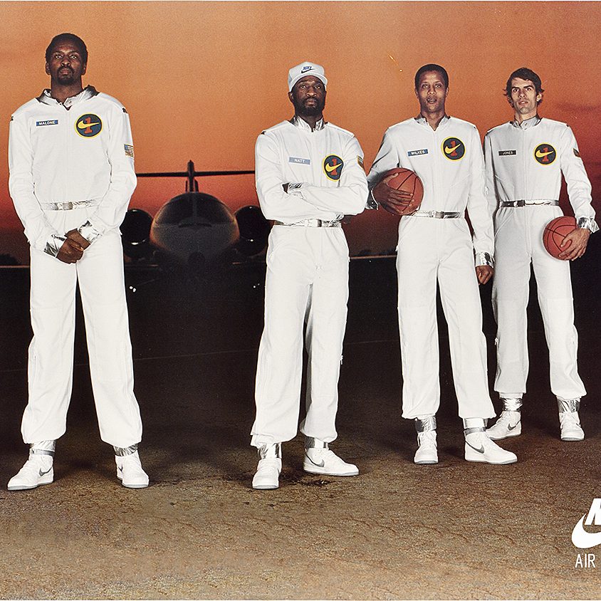 a poster featuring basketball stars in all white uniforms in front of a plane.