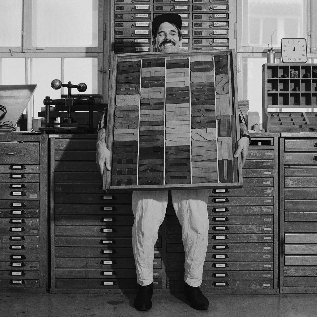 A photo of a man holding several letterpresses