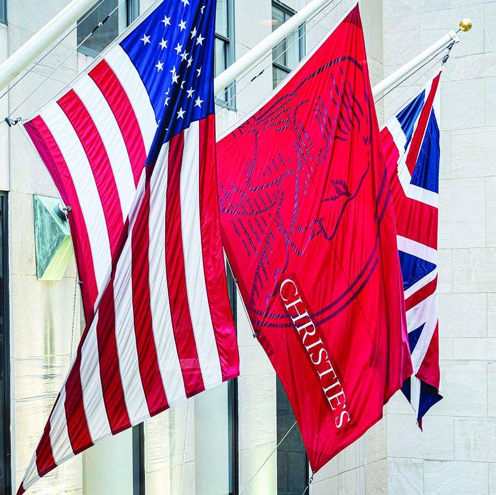 Photo of three flags hanging outside of a white building