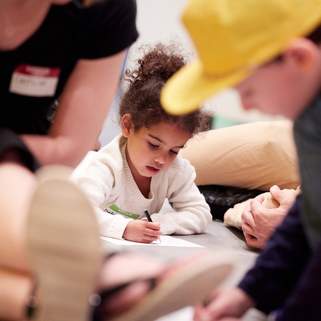 A photo of a child writing on a piece of paper in a museum
