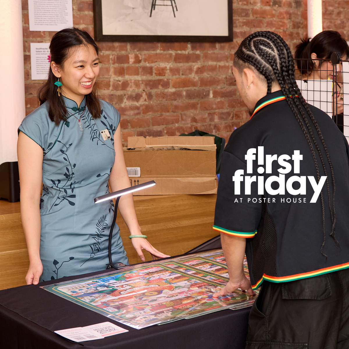 two people smiling and standing across from each other at table with a poster displayed on it