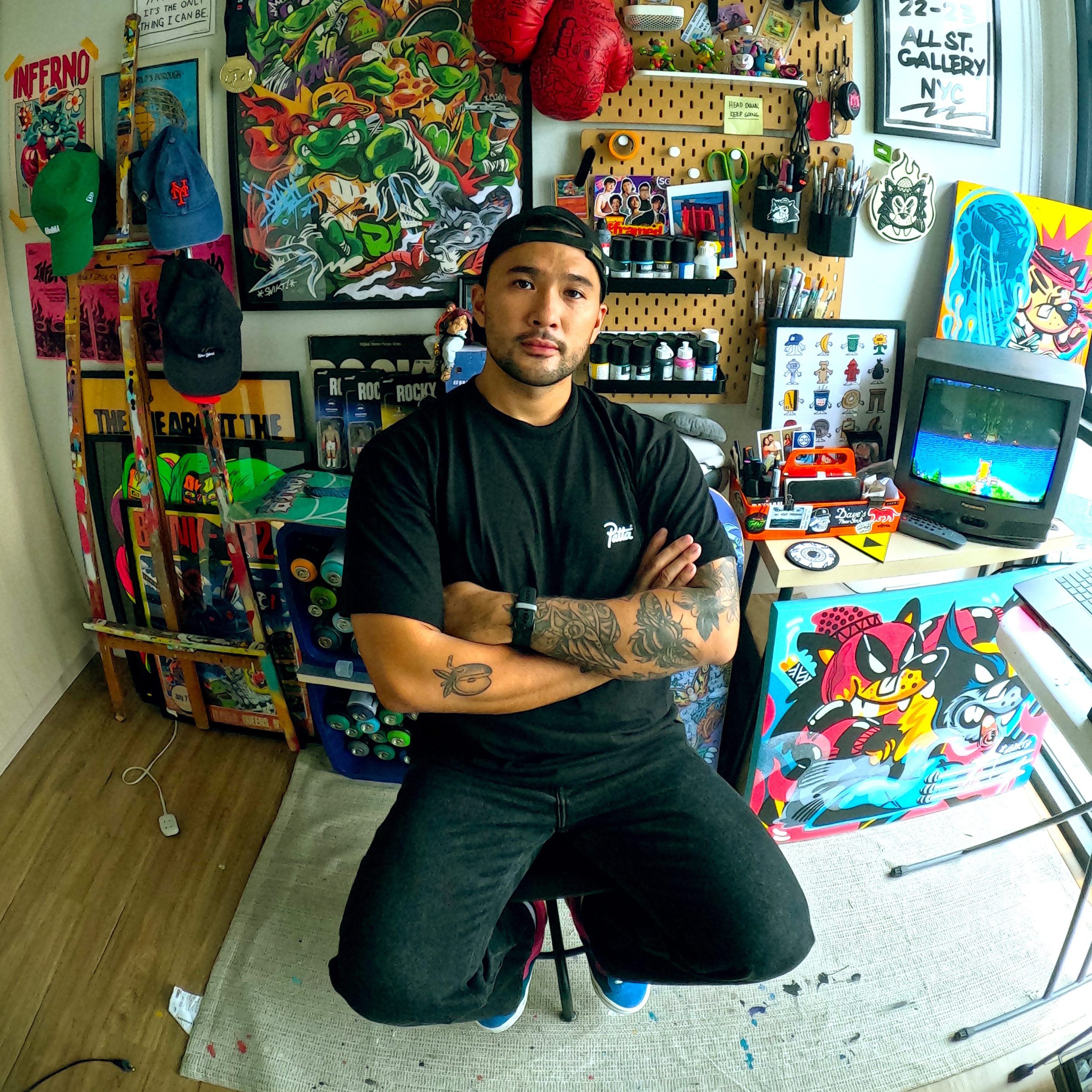 A man sitting with his arms folded in an art studio.
