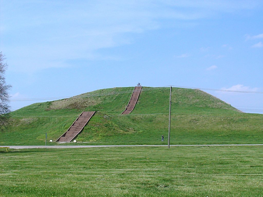 An image of green grass and hills with stone staircases leading up the hills, and a blue sky behind
