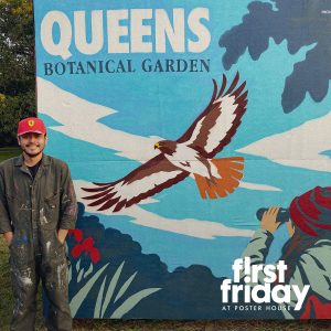 A man wearing coveralls standing in front of a mural of a bird.